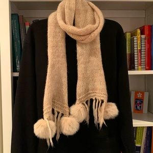 A playful 100% wool scarf with real fur pompons